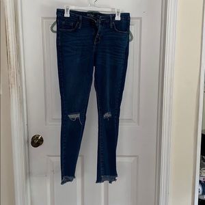 Mid rise stretch jeans. Raw hem and knee rips